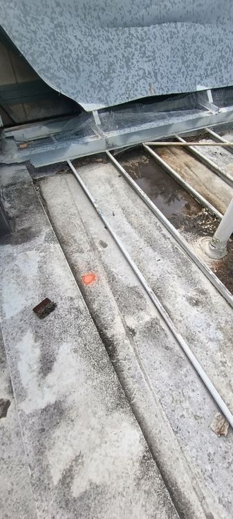 A narrow metal-roof channel beside a raised component before repair.