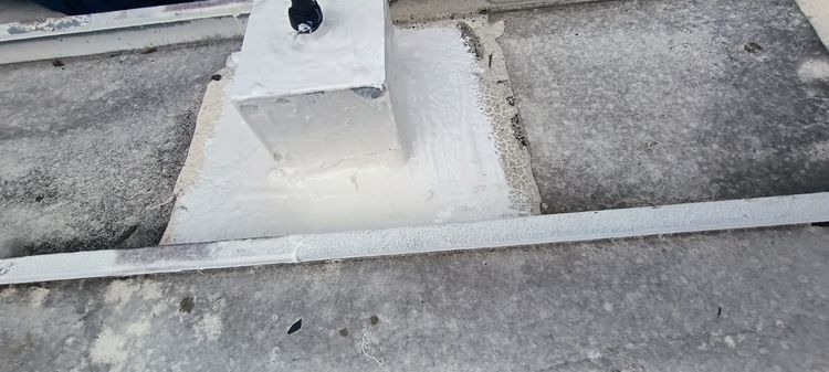 Sealant treatment around the base of a raised roof penetration.